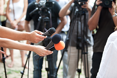 Billedet viser mikrofoner og kameraer der holdes frem i en interviewsituation